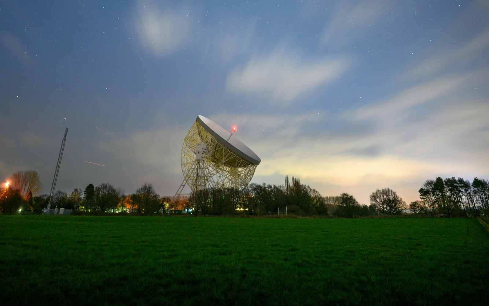 A large radio telescope in a field at Jodrell Bank.